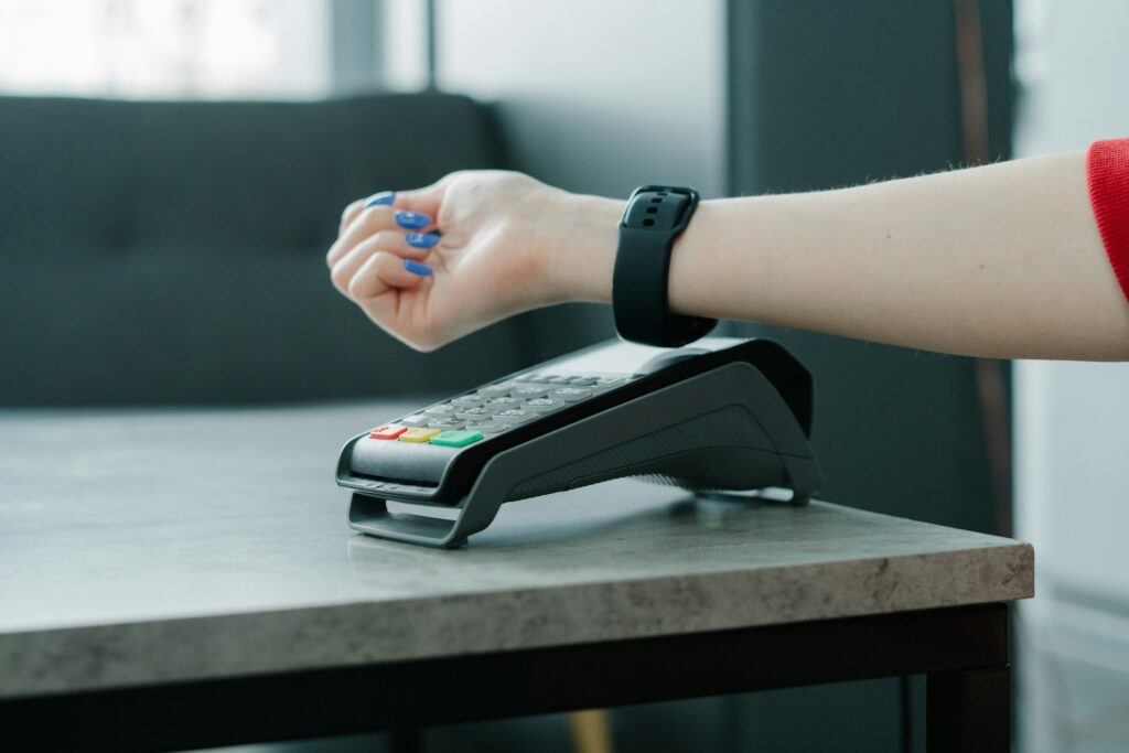 A close up of someone paying on a contactless card machine with their smartwatch