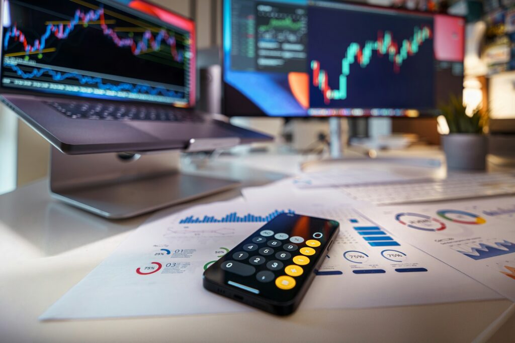 An example of a broker’s desk with a calculator, documentation, and computer screens for trading