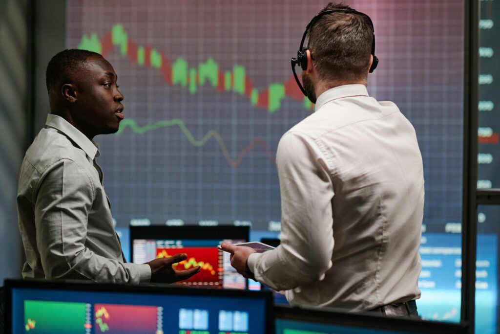 Two investors or brokers stand in a stock trading company room