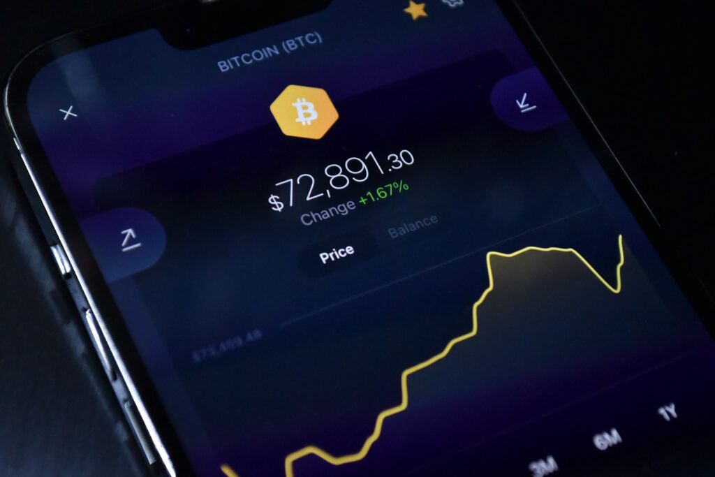 Close-up of a smartphone screen showing a bitcoin price chart and balance on a crypto trading app