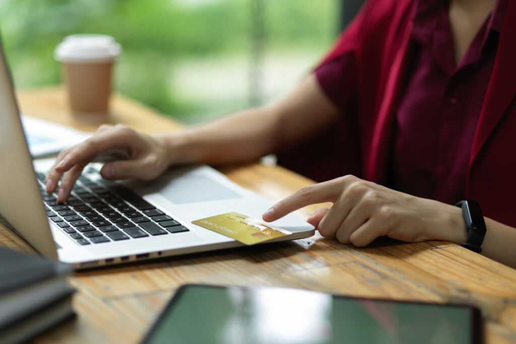 Someone working on their laptop, online banking, pointing at their debit card