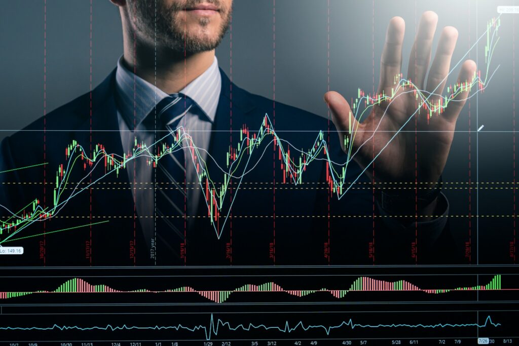 Business professional standing behind a stock market candlestick chart display