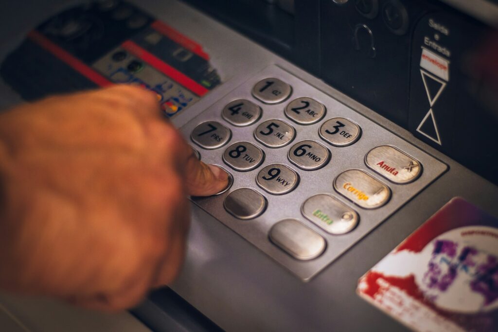 What is de-risking — and why is it happening to your business? 2 A close-up of a business owner using a pin code pad on an atm machine, checking the active status of their bank account