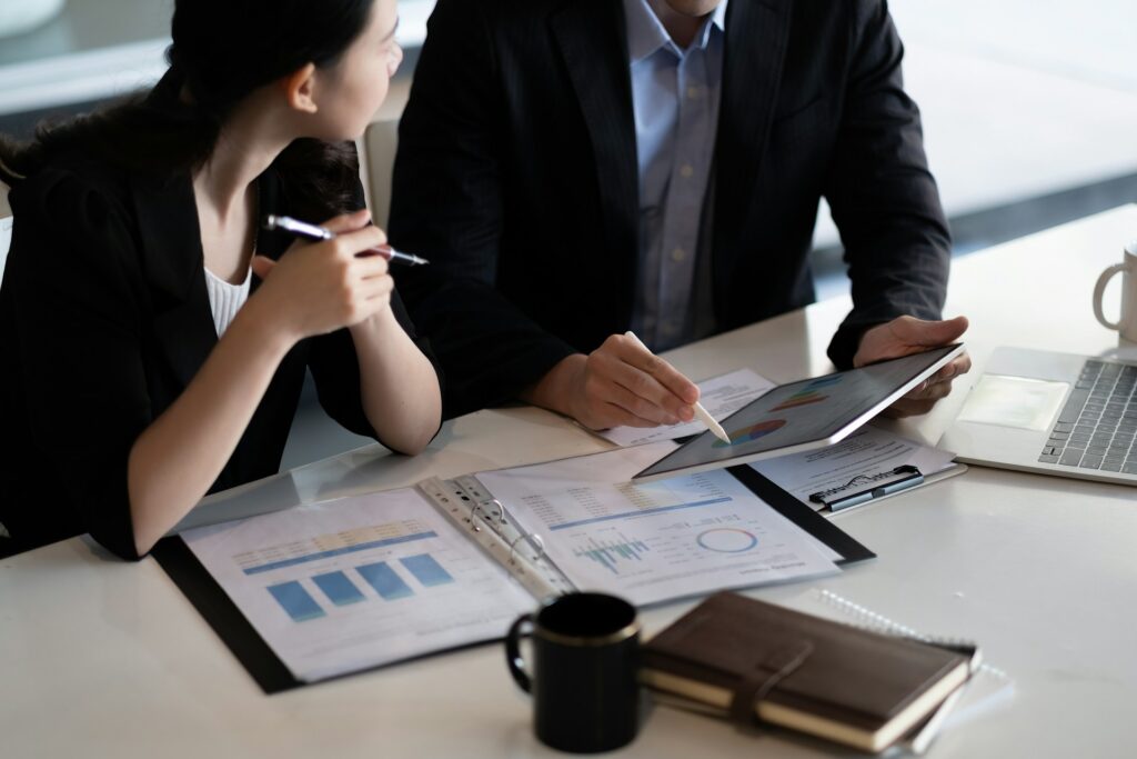 Two finance professionals reviewing financial reports and charts, the kind of due diligence behind an emi safeguarding account