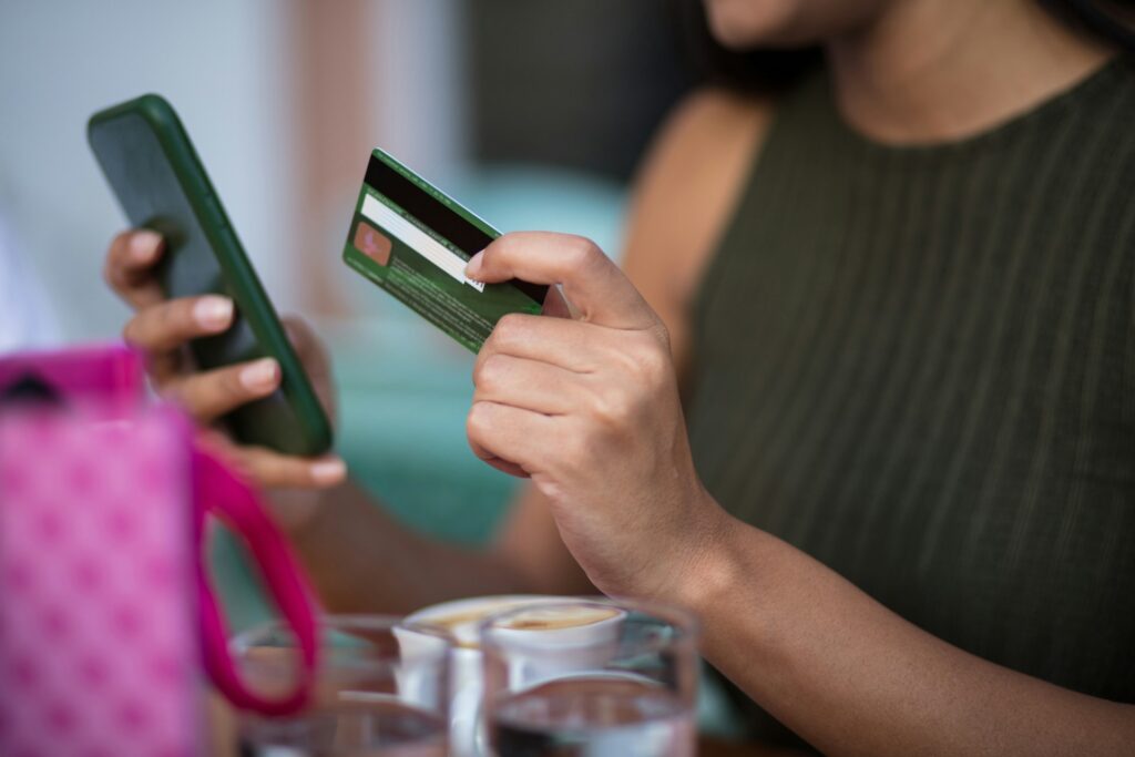 Person paying by card on their phone, representing the customer funds an EMI safeguarding account protects