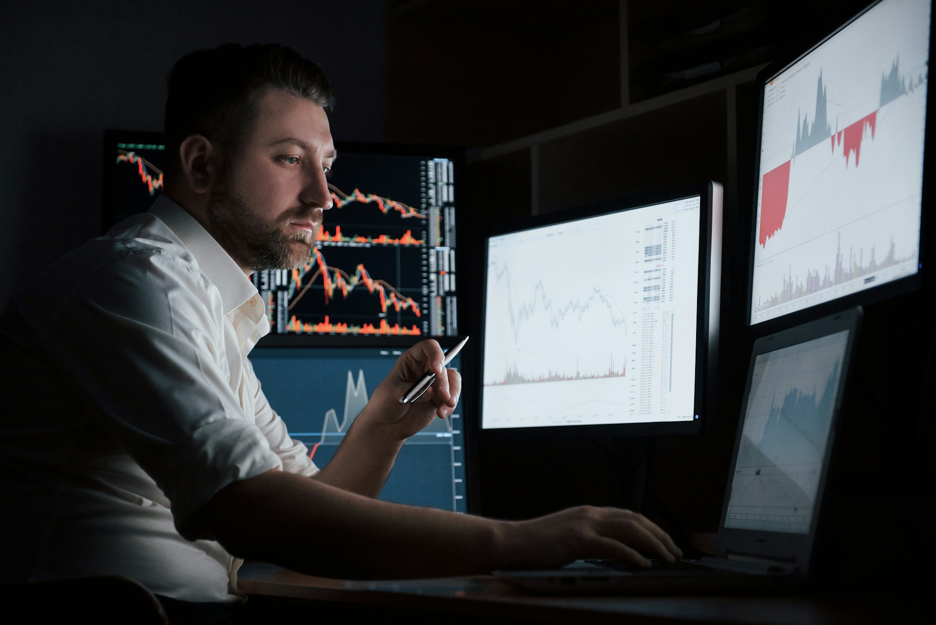 Man analysing market data at a desk with several trading monitors