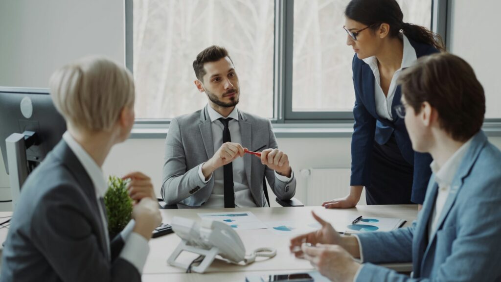 Colleagues discussing printed charts and documents around a meeting room table