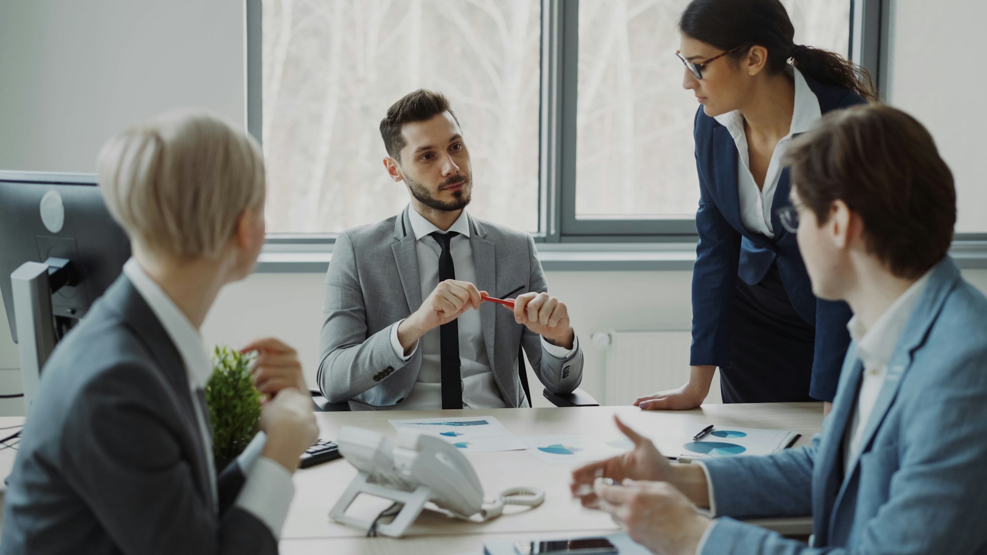 Colleagues discussing printed charts and documents around a meeting room table